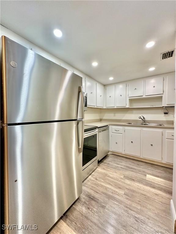 kitchen with white cabinets, stainless steel appliances, light hardwood / wood-style flooring, and sink