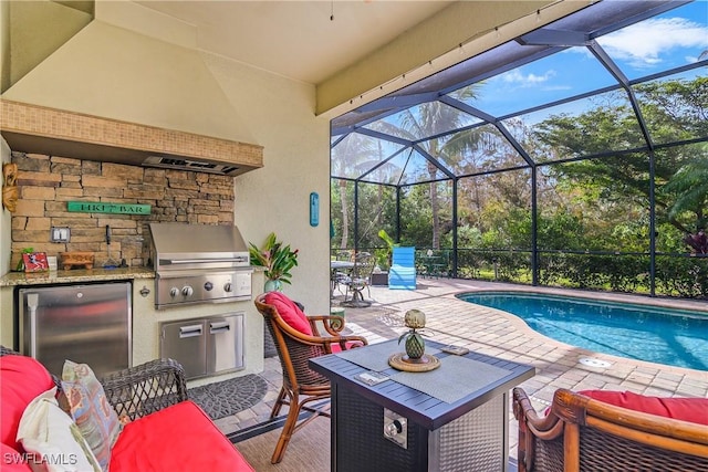 view of swimming pool with an outdoor kitchen, a grill, glass enclosure, and a patio area