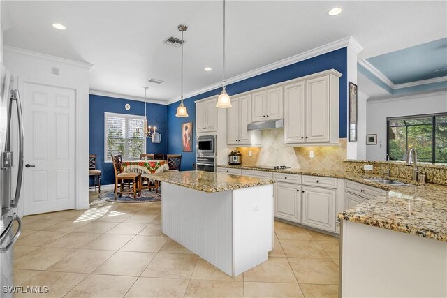 kitchen featuring sink, appliances with stainless steel finishes, light stone countertops, white cabinets, and decorative light fixtures