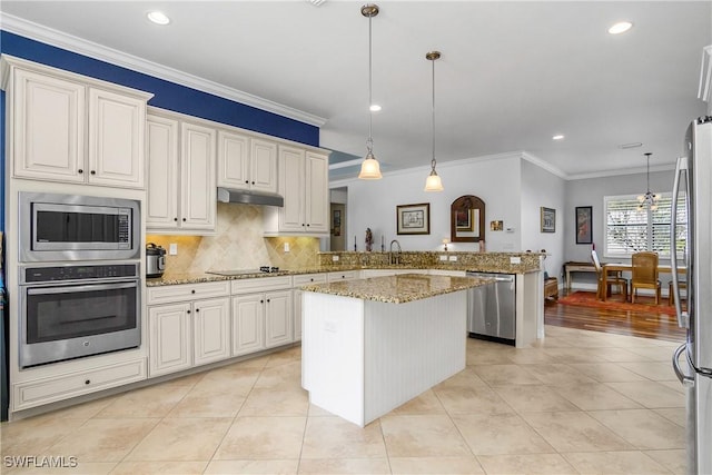 kitchen with appliances with stainless steel finishes, kitchen peninsula, pendant lighting, light stone countertops, and white cabinets