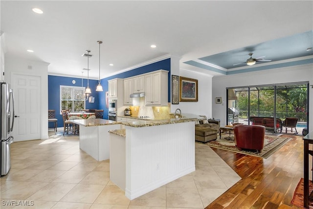 kitchen with light stone counters, light tile patterned floors, pendant lighting, stainless steel appliances, and white cabinets