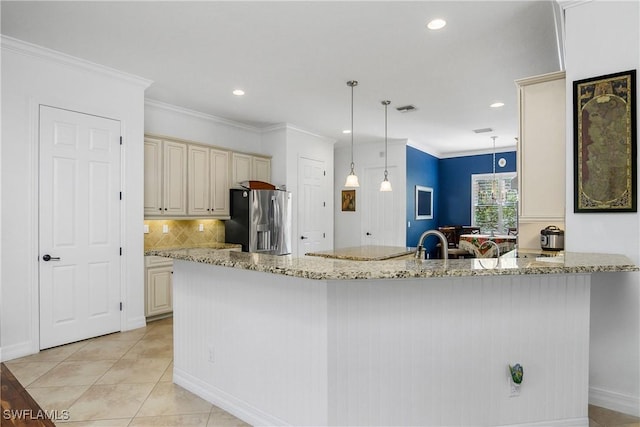 kitchen featuring pendant lighting, light tile patterned floors, cream cabinets, light stone countertops, and stainless steel fridge with ice dispenser