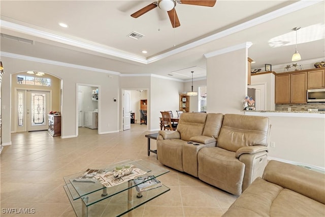 living room featuring a tray ceiling, ceiling fan, light tile patterned floors, and ornamental molding