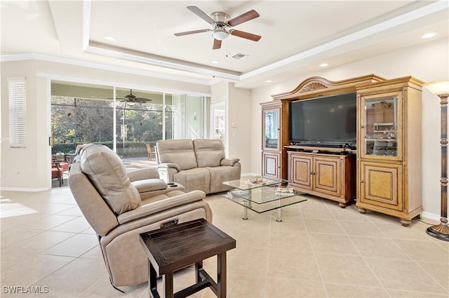 tiled living room featuring a raised ceiling, ceiling fan, and ornamental molding