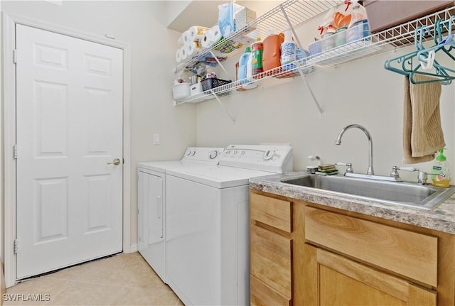 clothes washing area featuring washing machine and dryer, sink, and light tile patterned floors