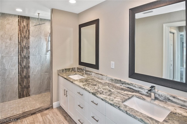 bathroom with a tile shower, hardwood / wood-style floors, and vanity