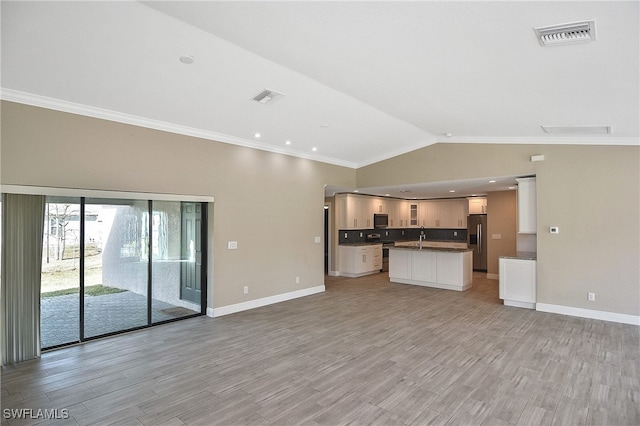 unfurnished living room featuring light wood-type flooring, vaulted ceiling, and crown molding