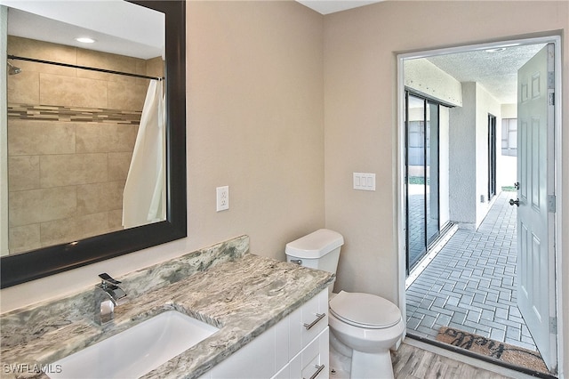 bathroom featuring a shower with curtain, toilet, vanity, and hardwood / wood-style flooring