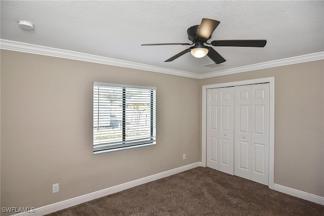 unfurnished bedroom with a textured ceiling, ceiling fan, crown molding, dark colored carpet, and a closet