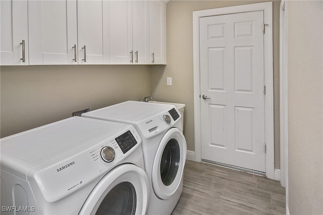 clothes washing area featuring washer and dryer, light hardwood / wood-style flooring, and cabinets