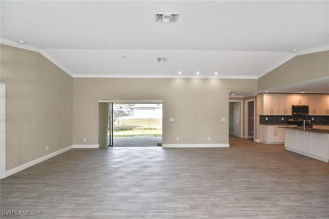 unfurnished living room featuring light hardwood / wood-style floors, crown molding, lofted ceiling, and sink