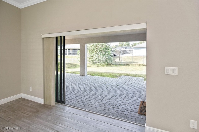 entryway with a healthy amount of sunlight, crown molding, and wood-type flooring