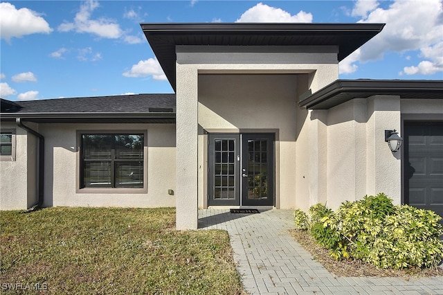 view of exterior entry with french doors and a lawn