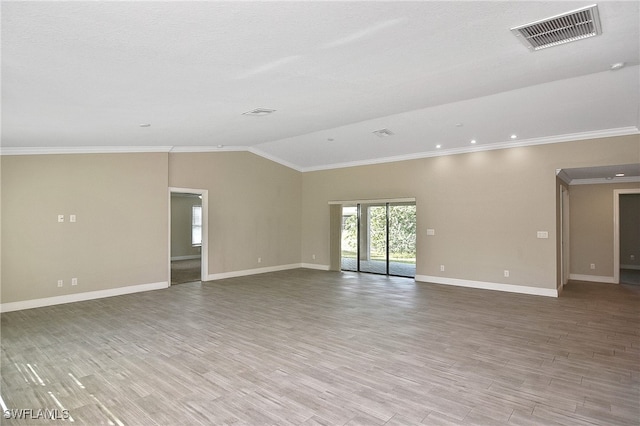 empty room featuring light hardwood / wood-style floors, ornamental molding, and vaulted ceiling