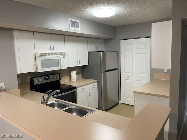 1885 Florida Club Dr Unit 8108, Naples, FL 34112 - kitchen with appliances with stainless steel finishes, a textured ceiling, light countertops, a peninsula, and white cabinetry