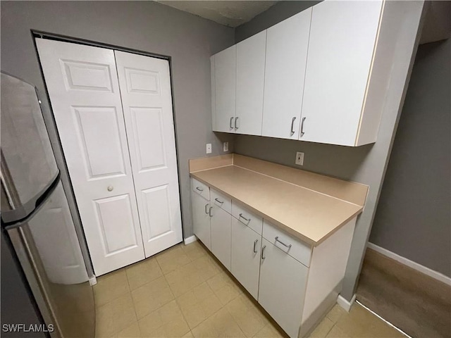 kitchen featuring white cabinetry and stainless steel refrigerator