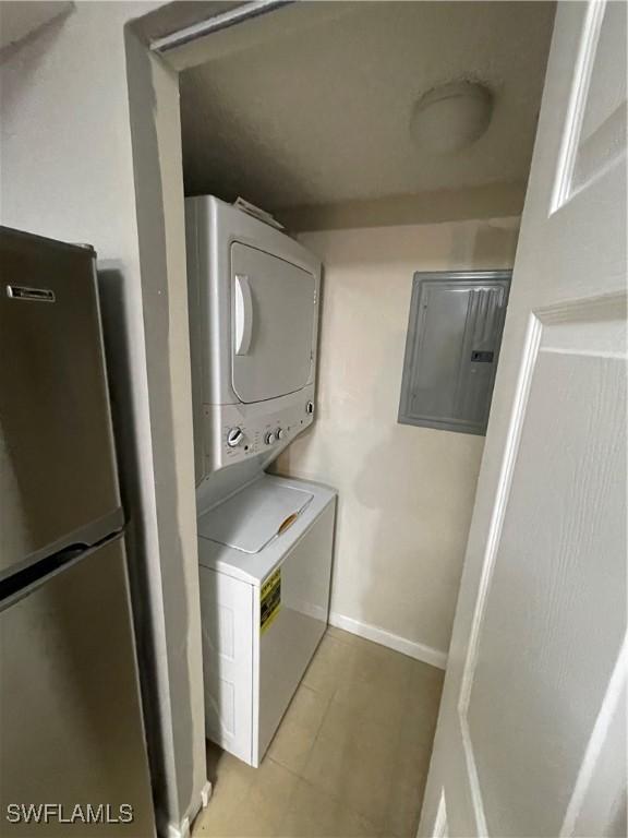 laundry area featuring electric panel and stacked washer and clothes dryer