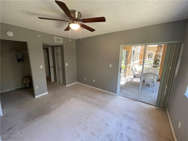 unfurnished bedroom with access to exterior, a textured ceiling, light colored carpet, ceiling fan, and a closet