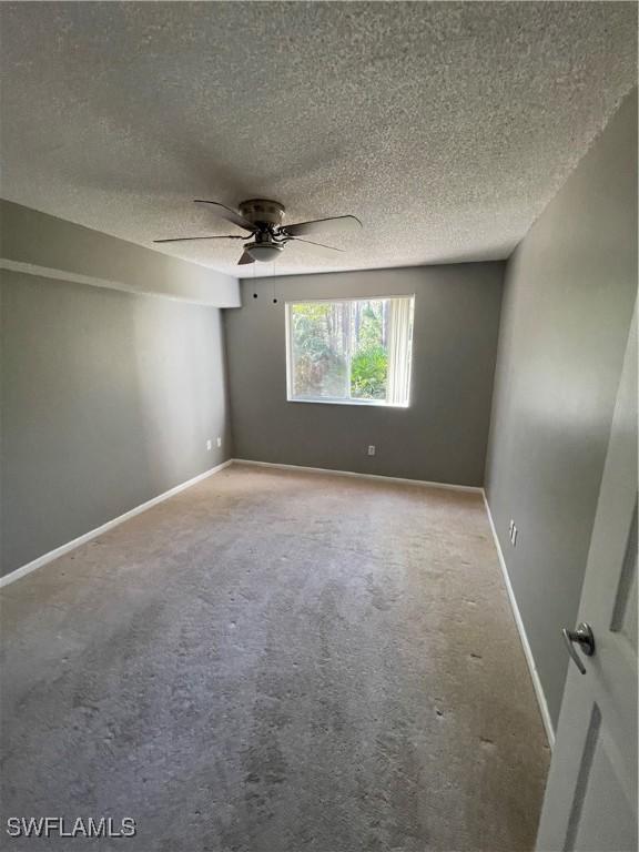 spare room featuring a textured ceiling, carpet floors, and ceiling fan