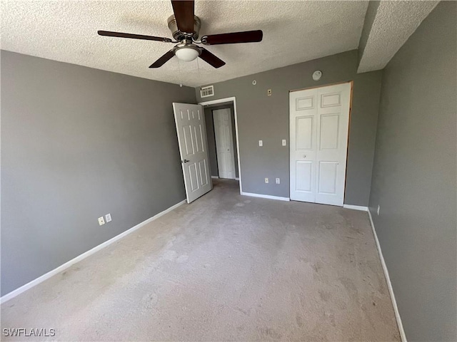 unfurnished bedroom with carpet flooring, ceiling fan, a textured ceiling, and a closet