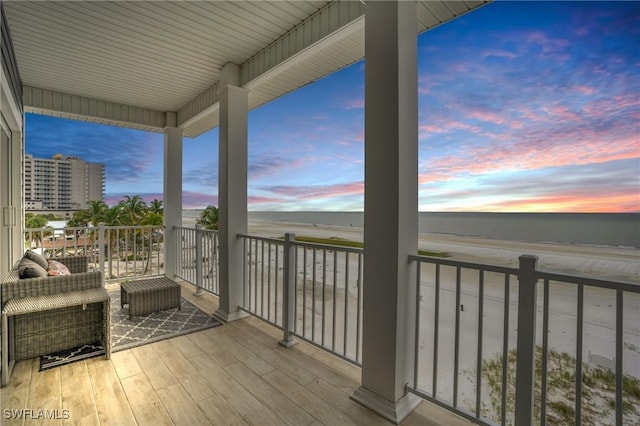 balcony at dusk featuring a water view