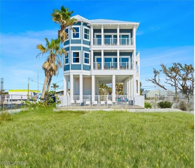 back of house with a balcony and a lawn