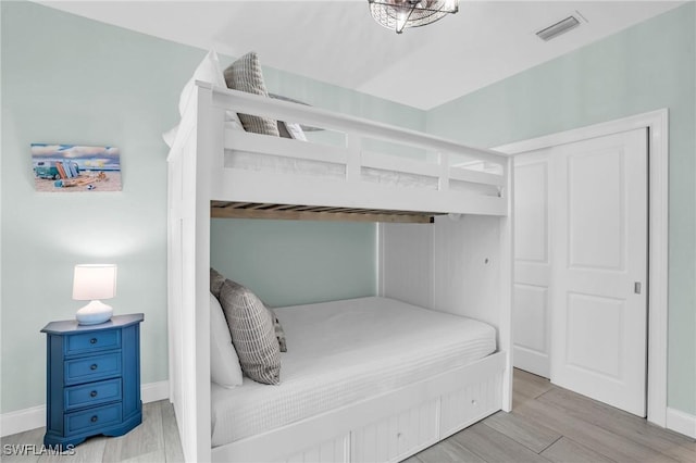 bedroom with light wood-style floors, visible vents, and baseboards