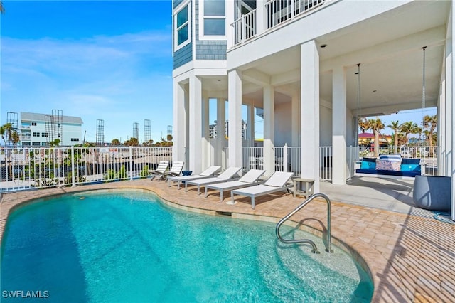 community pool with a patio, fence, and a city view