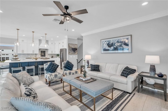 living room featuring crown molding, recessed lighting, visible vents, light wood-style flooring, and a ceiling fan