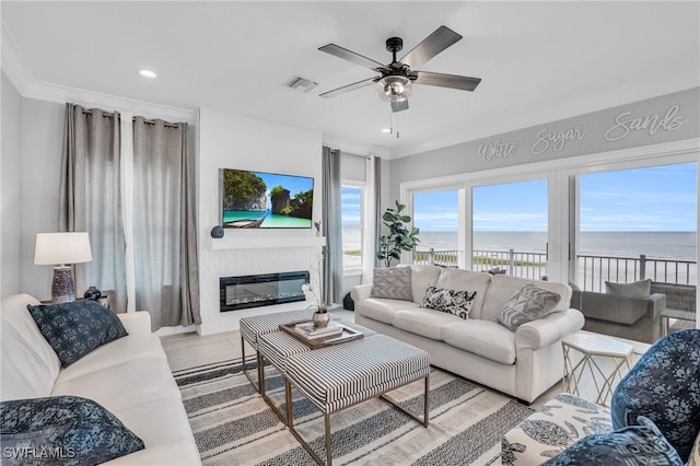 living room featuring recessed lighting, visible vents, a ceiling fan, ornamental molding, and a glass covered fireplace