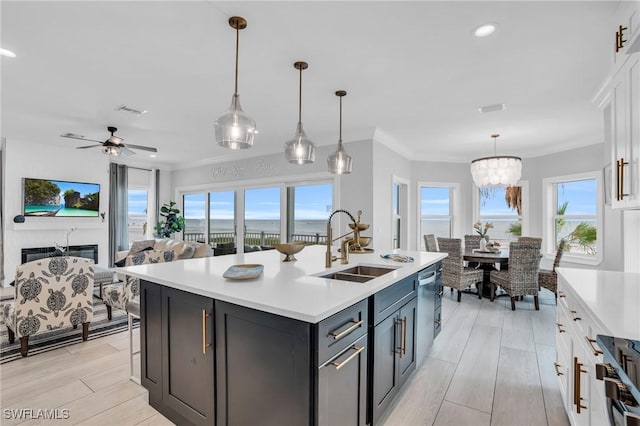 kitchen featuring an island with sink, white cabinetry, light countertops, and decorative light fixtures