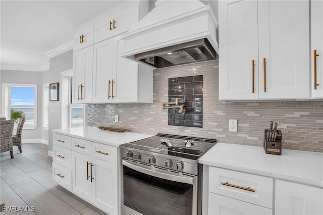 kitchen featuring light countertops, white cabinets, stainless steel range with electric cooktop, and premium range hood