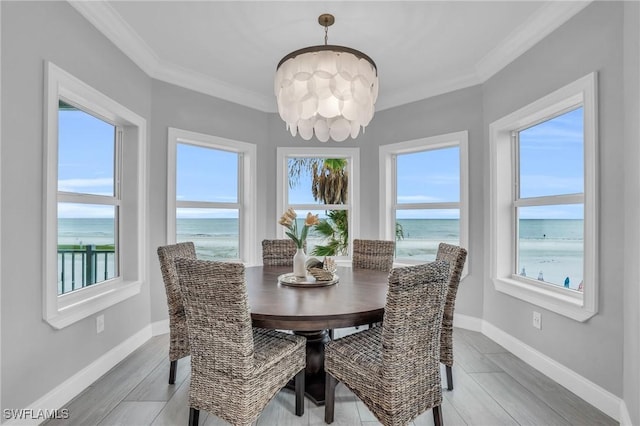 dining room with a chandelier, a water view, crown molding, and baseboards