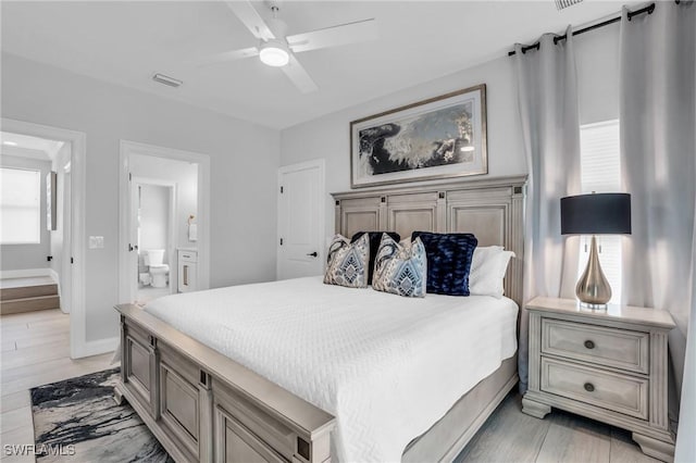 bedroom with baseboards, visible vents, a ceiling fan, ensuite bathroom, and light wood-type flooring