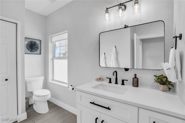 bathroom featuring baseboards, vanity, toilet, and wood finished floors