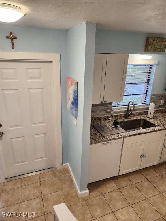 kitchen with dark stone counters, white cabinets, sink, decorative backsplash, and light tile patterned floors