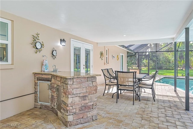 view of patio with glass enclosure and an outdoor wet bar