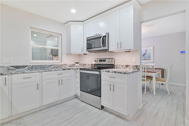 kitchen with white cabinets, light stone counters, and appliances with stainless steel finishes