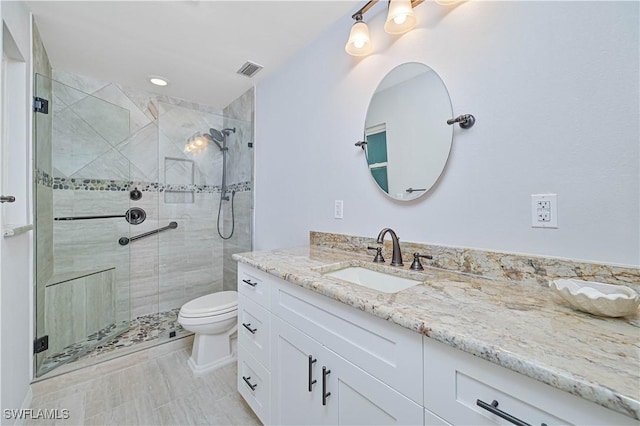 bathroom featuring tile patterned flooring, vanity, toilet, and a shower with shower door