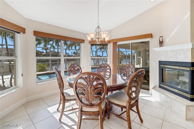 tiled dining space featuring a tile fireplace, lofted ceiling, and a healthy amount of sunlight