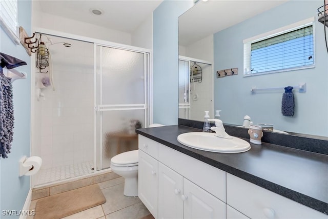 bathroom featuring tile patterned flooring, vanity, toilet, and walk in shower