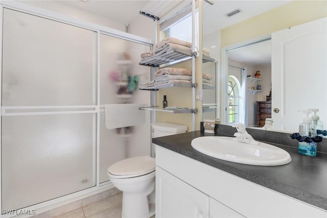 bathroom featuring tile patterned flooring, vanity, toilet, and walk in shower