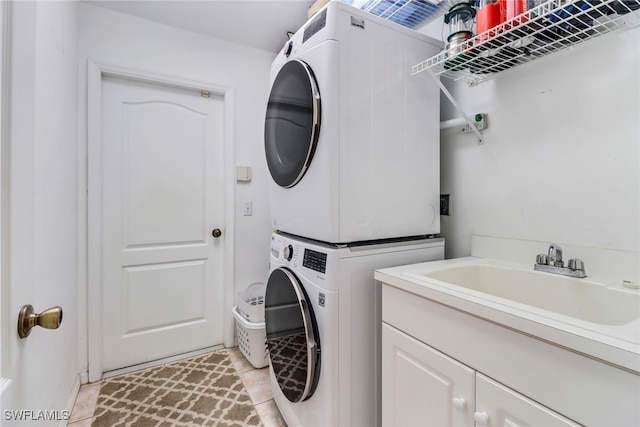 laundry area featuring cabinets, stacked washing maching and dryer, sink, and light tile patterned floors