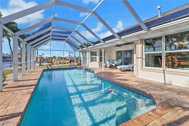 view of swimming pool featuring ceiling fan, a patio area, and glass enclosure