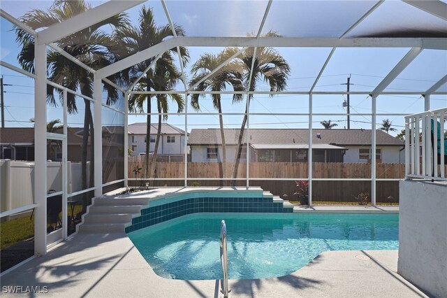 view of swimming pool featuring glass enclosure and a patio area