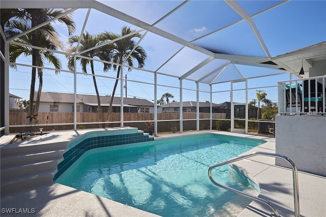 view of swimming pool with glass enclosure and a patio