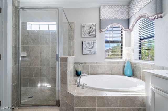 bathroom featuring plus walk in shower, vanity, and a healthy amount of sunlight