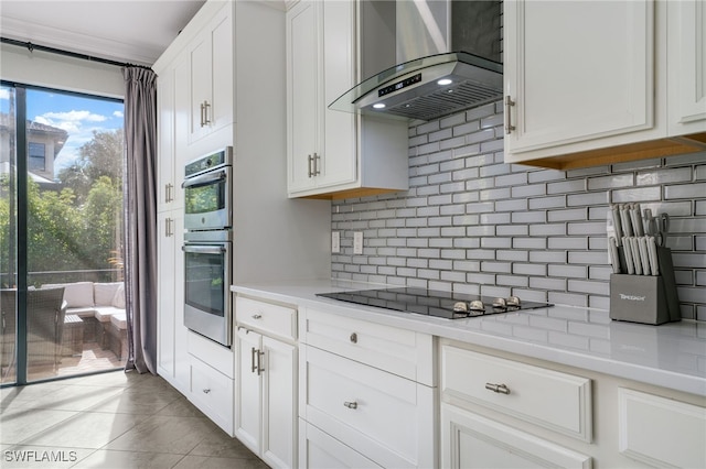 kitchen with white cabinets, black cooktop, tasteful backsplash, and wall chimney exhaust hood