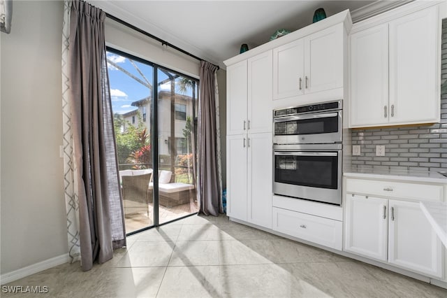 kitchen featuring decorative backsplash, light tile patterned floors, white cabinetry, and double oven