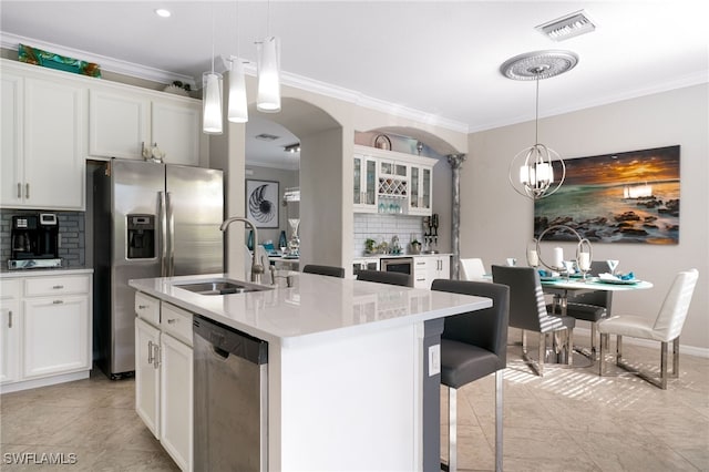 kitchen with appliances with stainless steel finishes, backsplash, white cabinetry, and hanging light fixtures